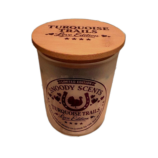 Turquoise Trails Love Edition soy candle in a frosted glass jar with wood lid and Snoody Scents horseshoe label